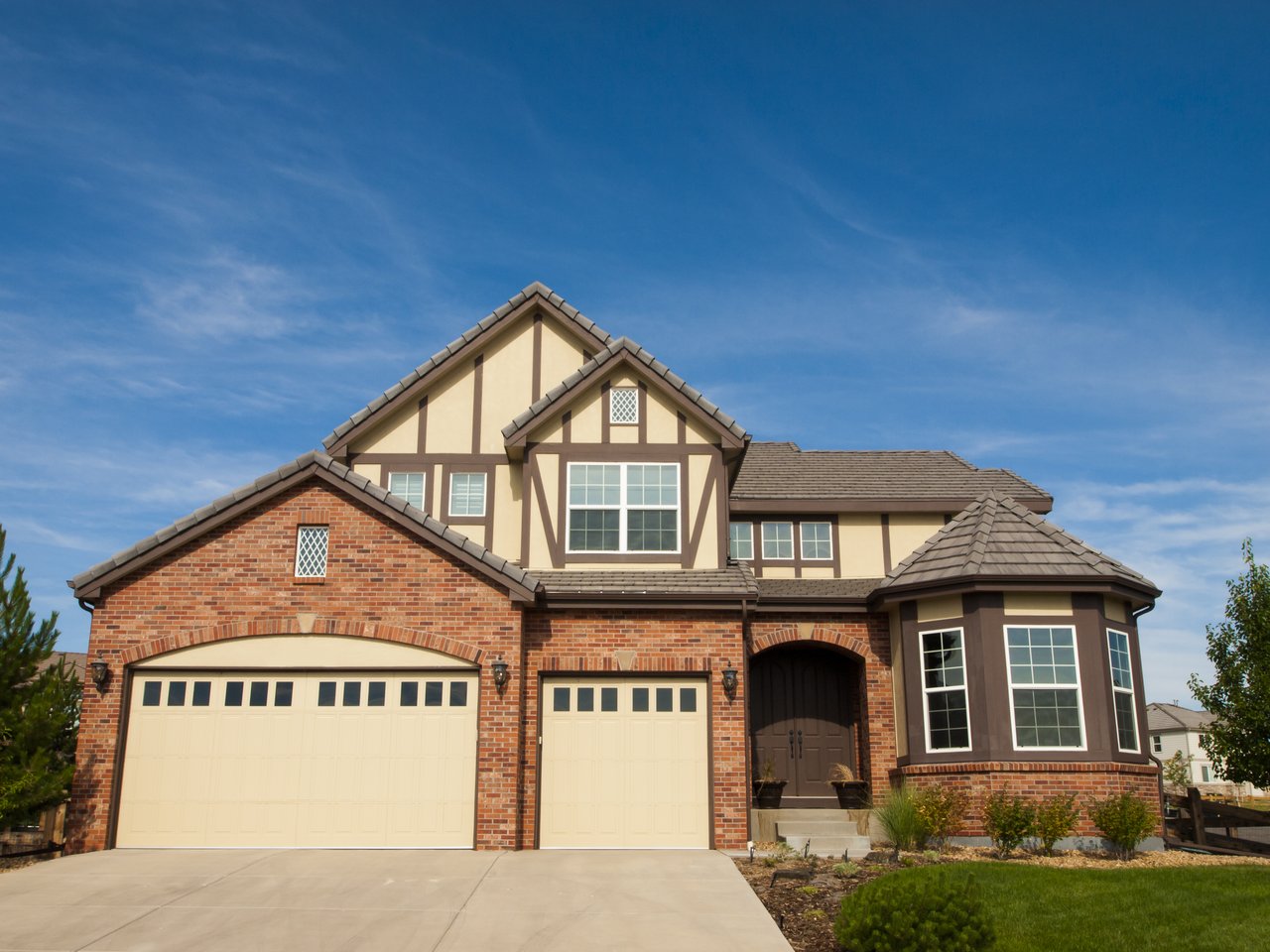 Two-story brick and stucco home with two garage doors, a bay window, and landscaped front yard.