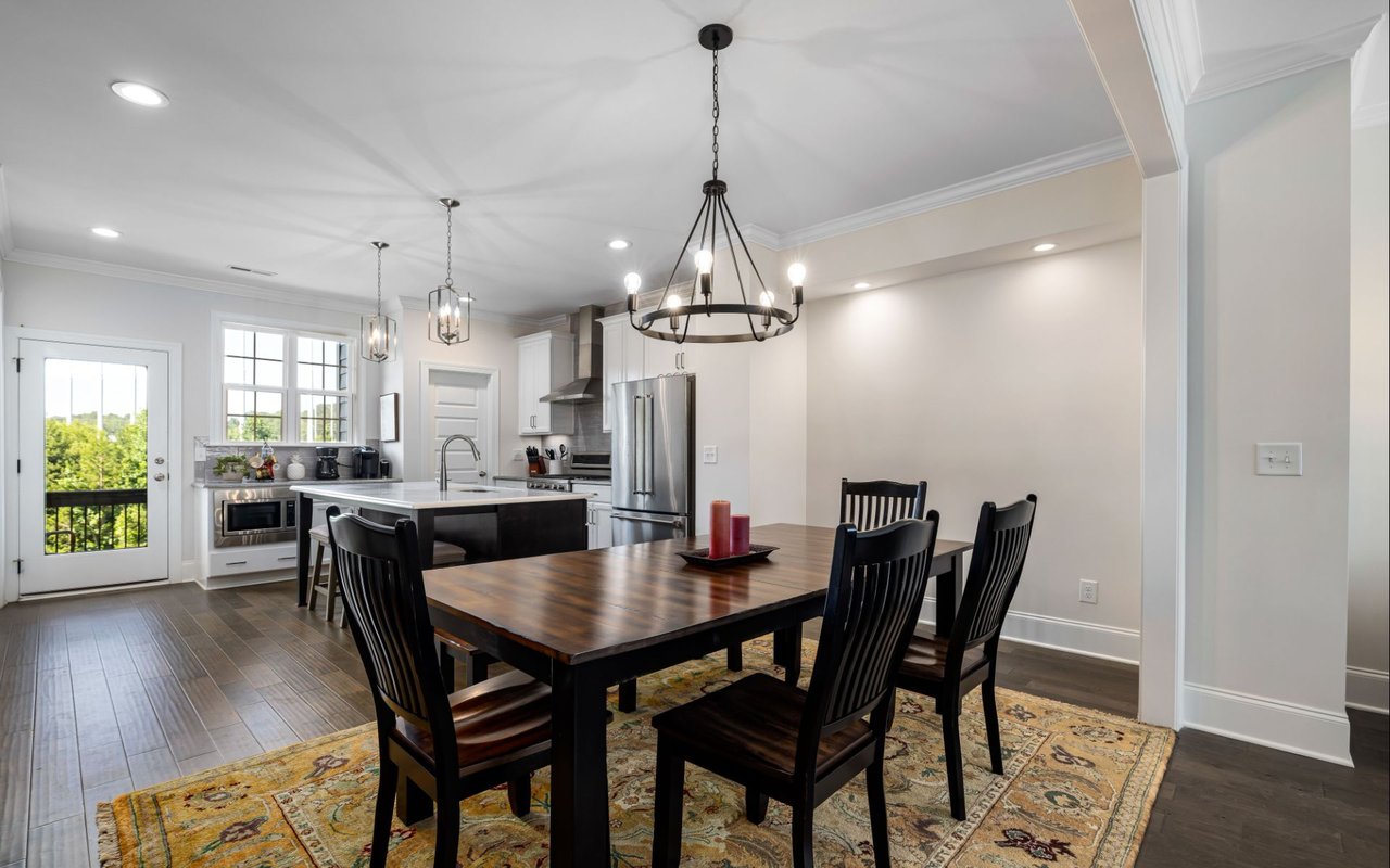 Open-plan kitchen and dining area with a dark wood table, white cabinetry, and stainless steel appliances.