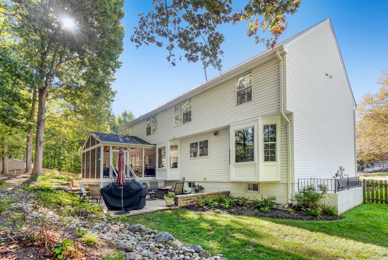 Rear exterior of a two-story home with a screened porch and landscaped yard.