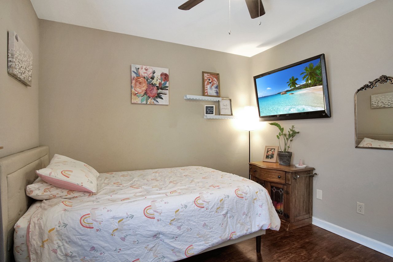 A cozy bedroom featuring a bed, a television, and a mirror, creating a comfortable and inviting atmosphere.