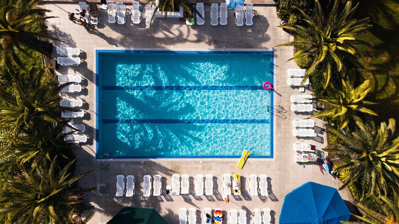 Aerial view of a swimming pool surrounded by lounge chairs and palm trees.