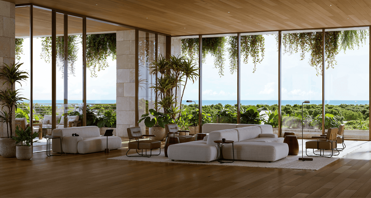 Living room with pale sofas and floor-to-ceiling windows overlooking the ocean.