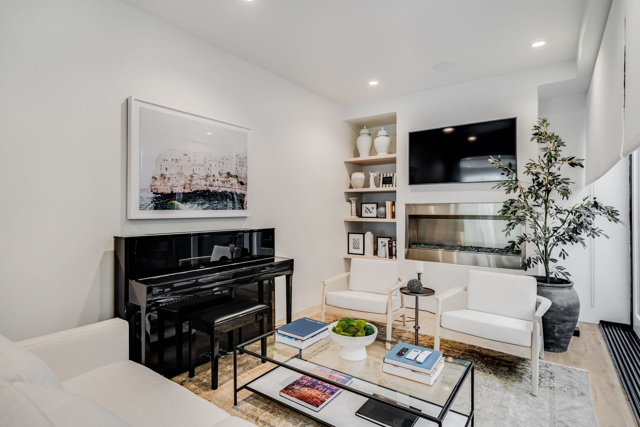 Furnished living room with a black piano, built-in fireplace, television, and white seating.