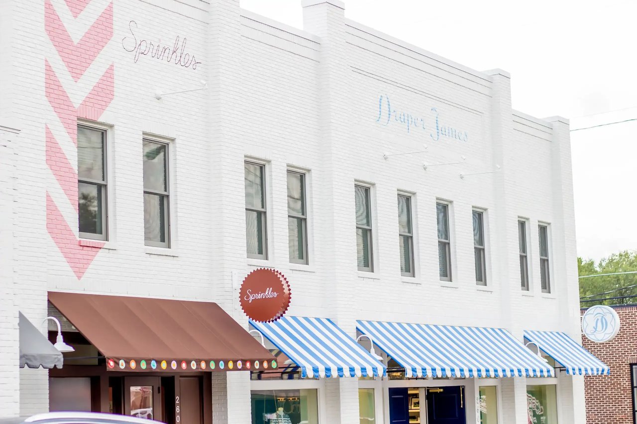 White brick storefront with a pink chevron, striped awnings, and Sprinkles signage.