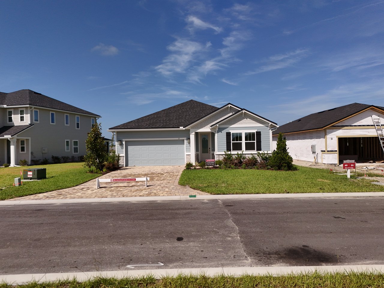 Gray single-story home with a two-car garage, paver driveway, and landscaped front yard.