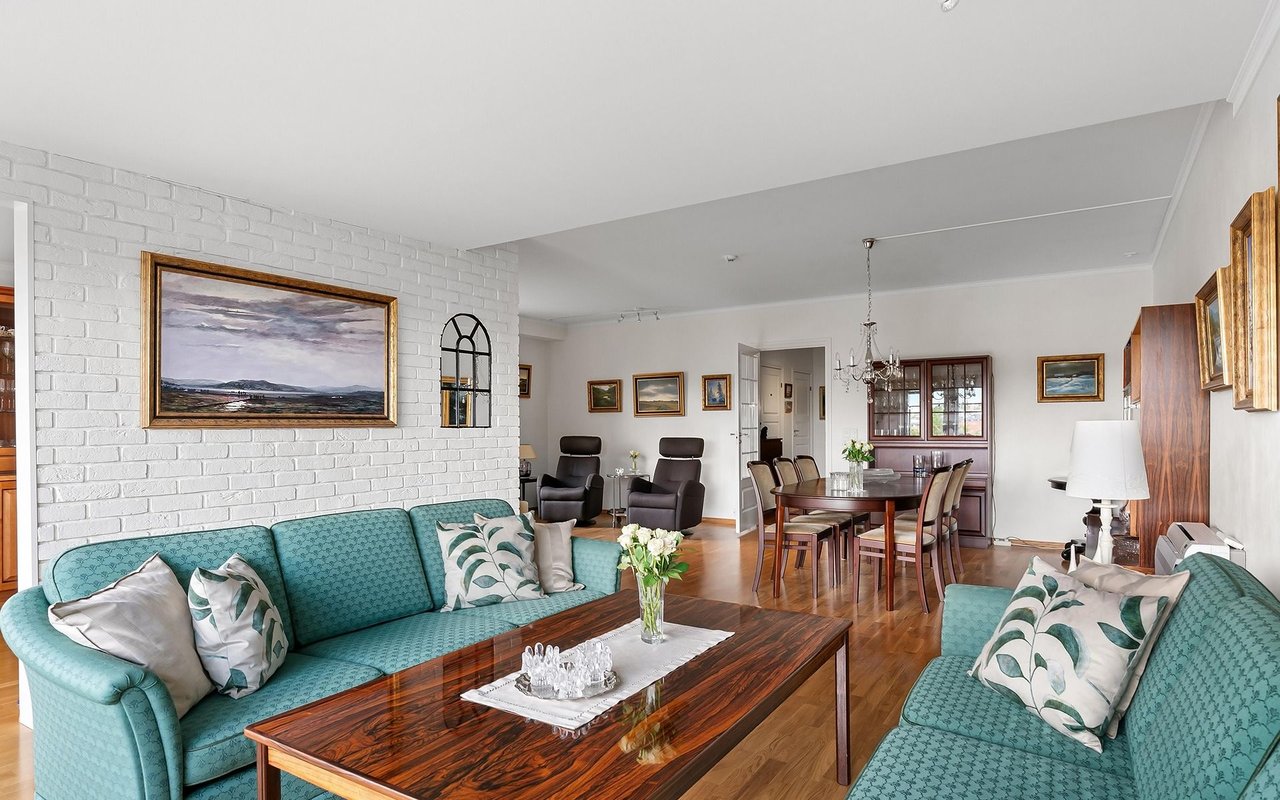 Living room with turquoise sofas, a dark wood coffee table, and an adjoining dining area.