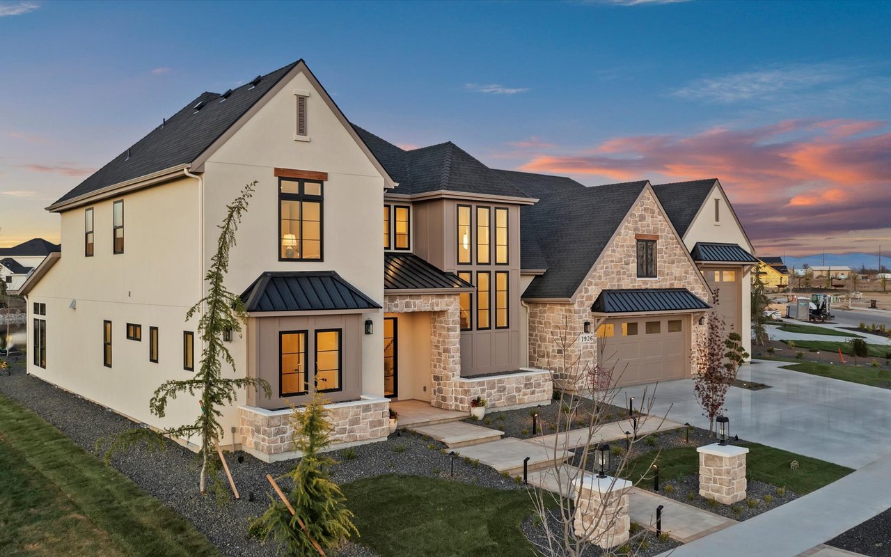 Front exterior of the home from the southwest - beige stucco, natural stone, black steel windows