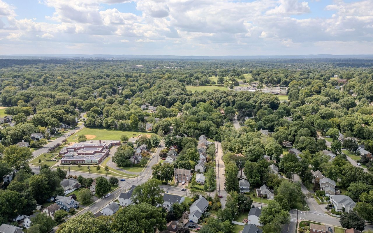 Aerial view of Montclair’s tree-lined homes and streets, with a large institutional building nearby.
