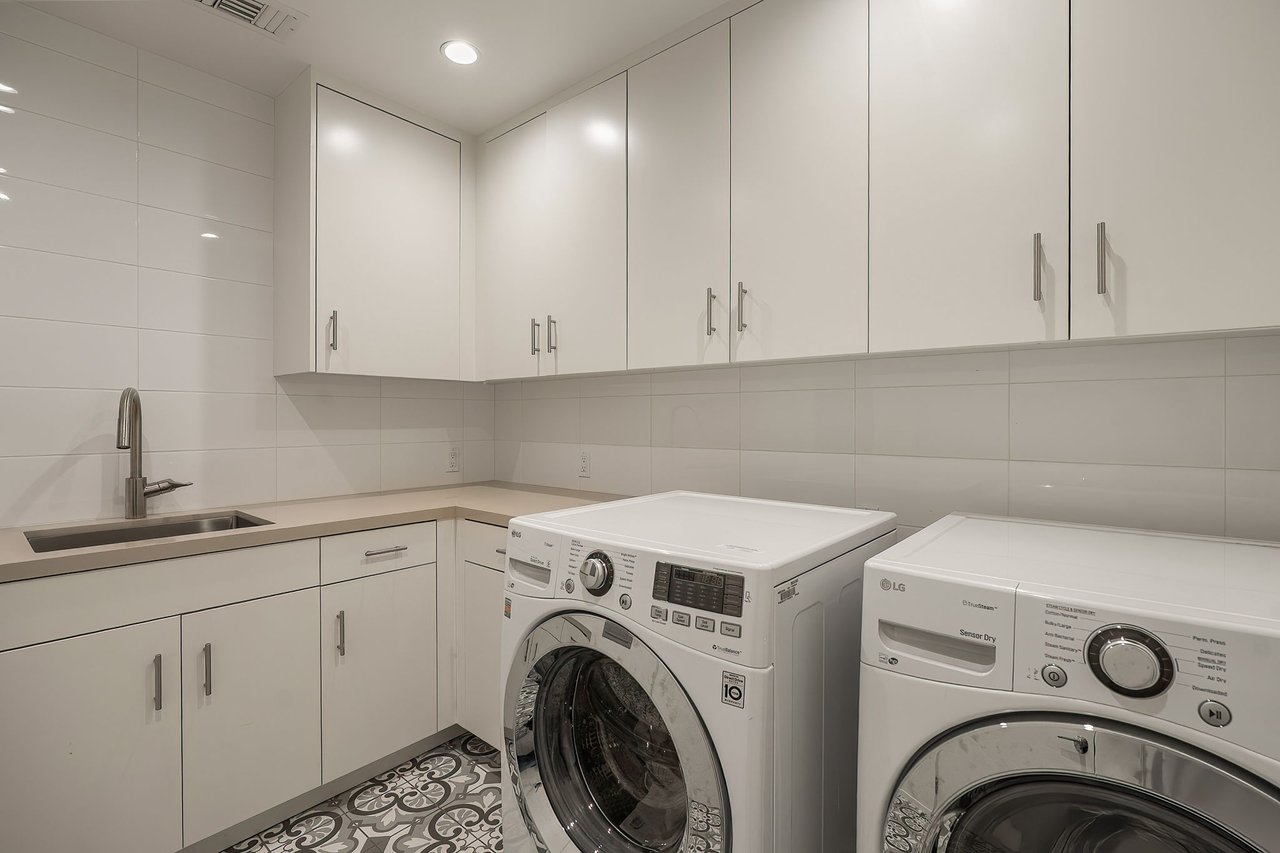 Laundry room with white cabinetry, a utility sink, and front-loading washer and dryer.