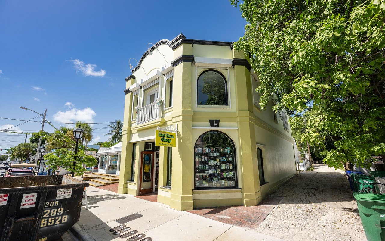 Pale yellow corner shop with arched windows and a Key Lime Shop sign beneath a leafy tree.