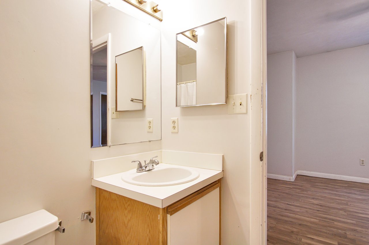 A clean bathroom featuring a sink, toilet, and mirror, showcasing a modern and functional design.