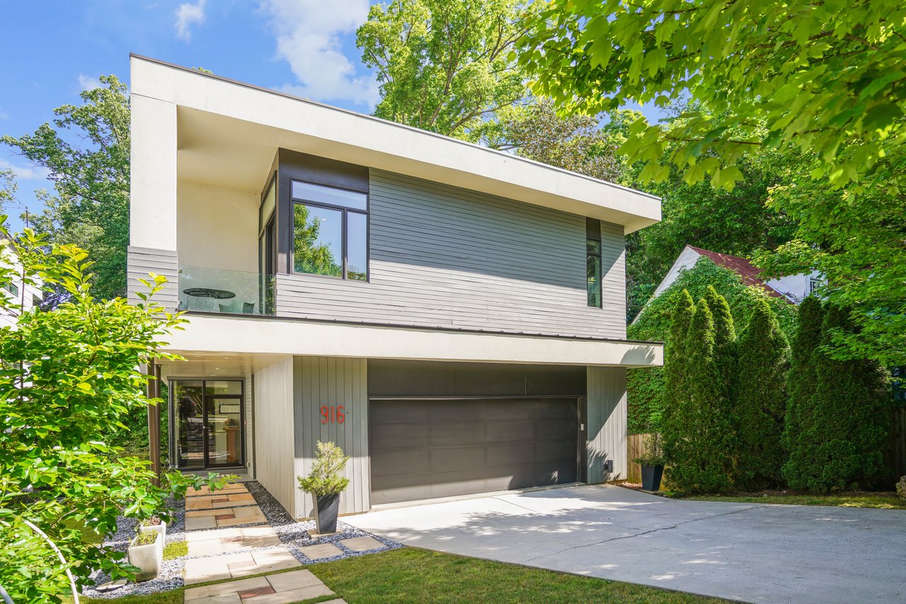 Modern two-story home with a flat roof, wide garage, and landscaped front walkway.