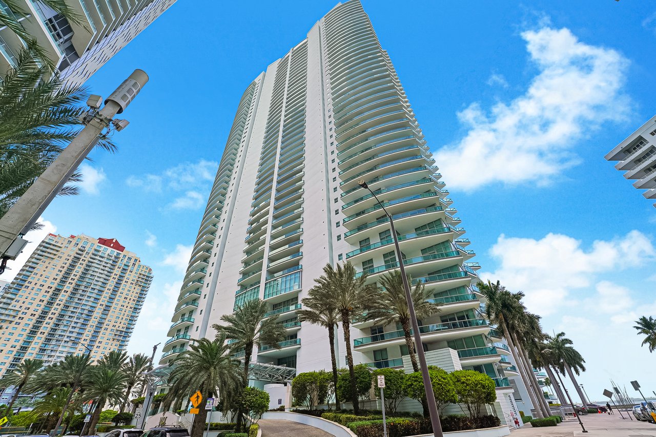 Street-level exterior of Jade Residences at 1331 Brickell Bay Drive with curved balconies and palm-lined entrance