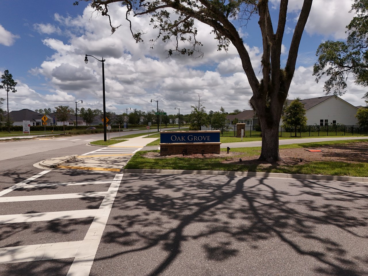 Oak Grove neighborhood entrance sign beside a shaded residential street.