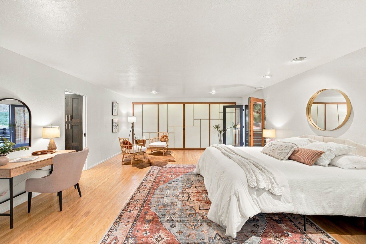 Bedroom with a large white bed, patterned rug, and wood-framed sliding panels.