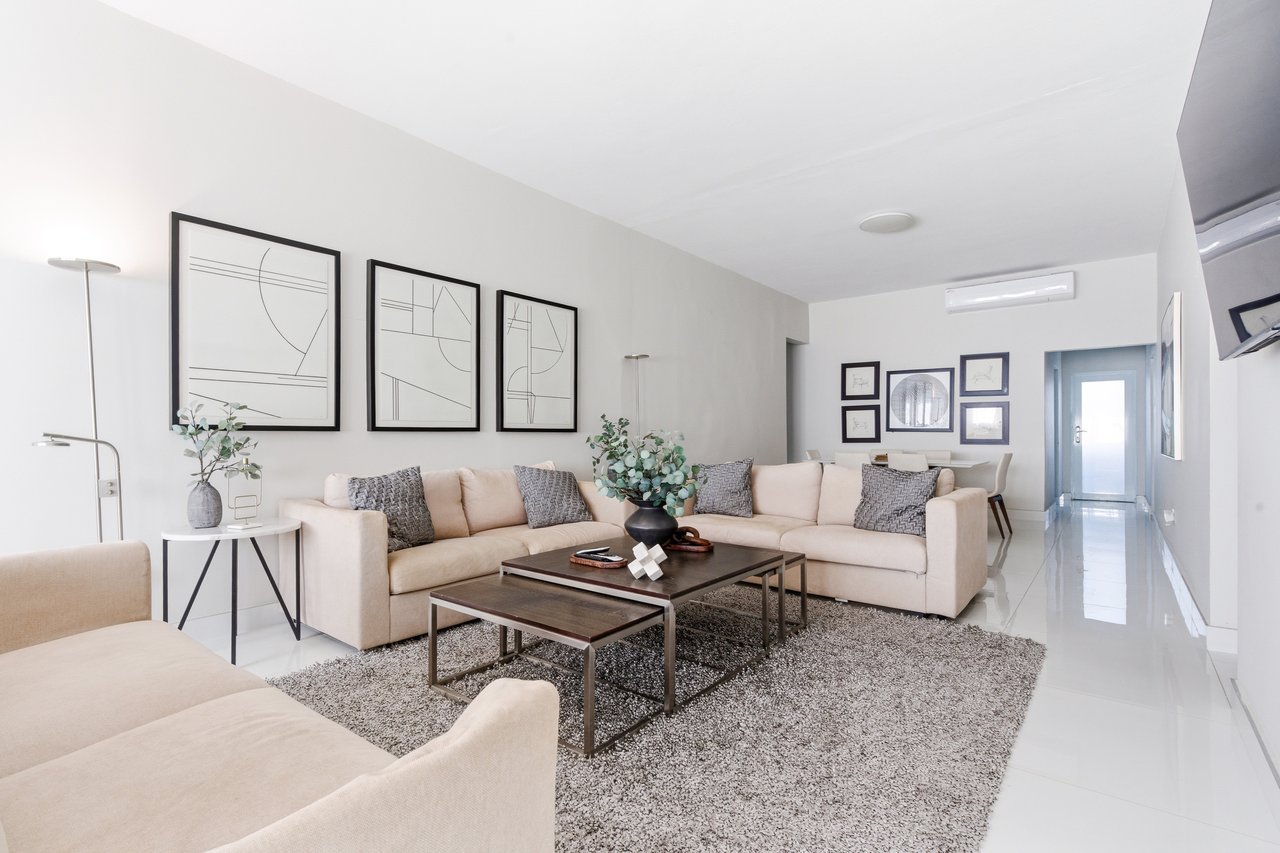 Furnished living room with a cream sectional, nested coffee tables, and abstract wall art.