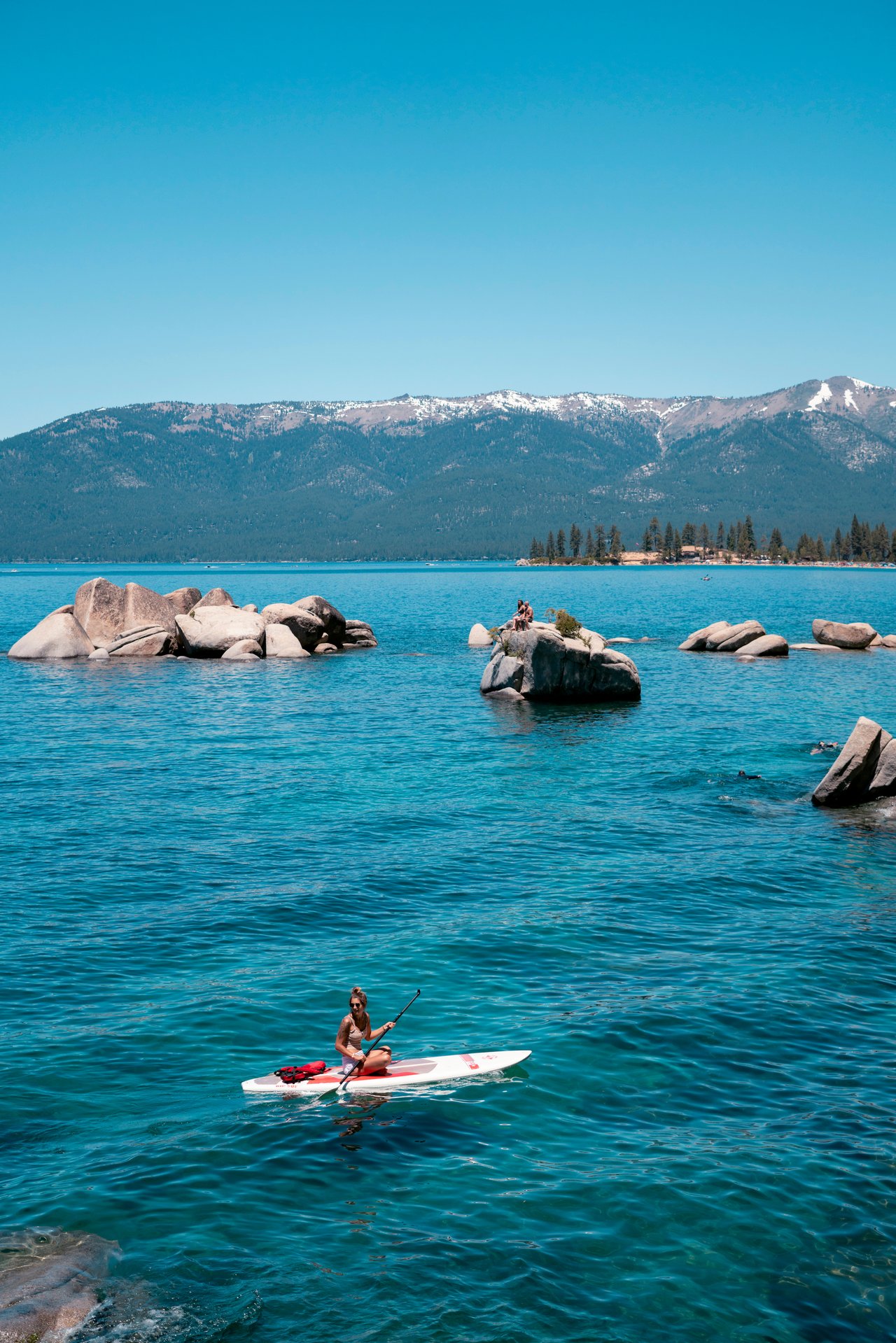 Kayakers and hikers enjoying Lake Tahoe in May with clear blue water, mountain views, and spring sunshine