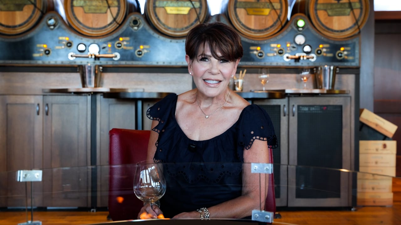Mela Fratarcangeli seated in a tasting room with wooden barrels behind her.