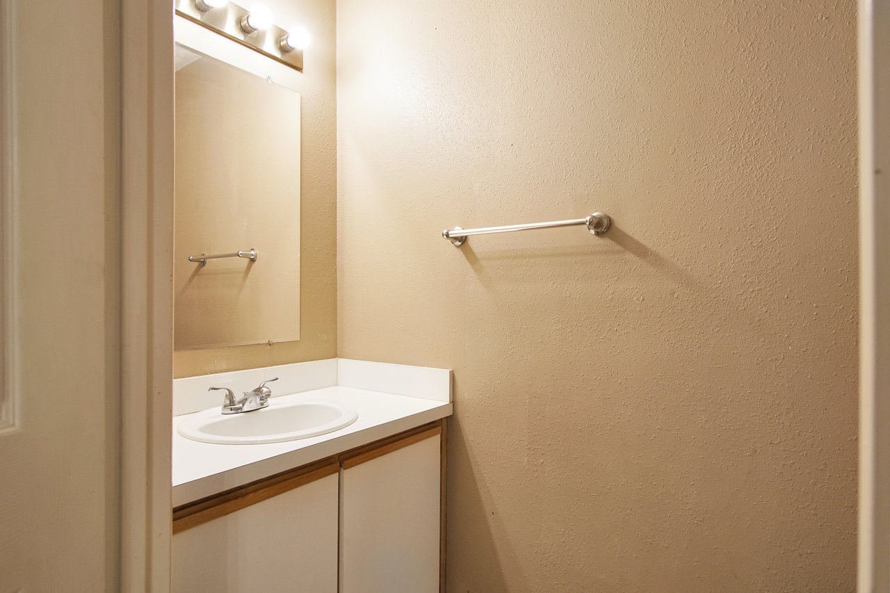 A clean bathroom featuring a modern sink and a large mirror reflecting the bright, well-lit space.