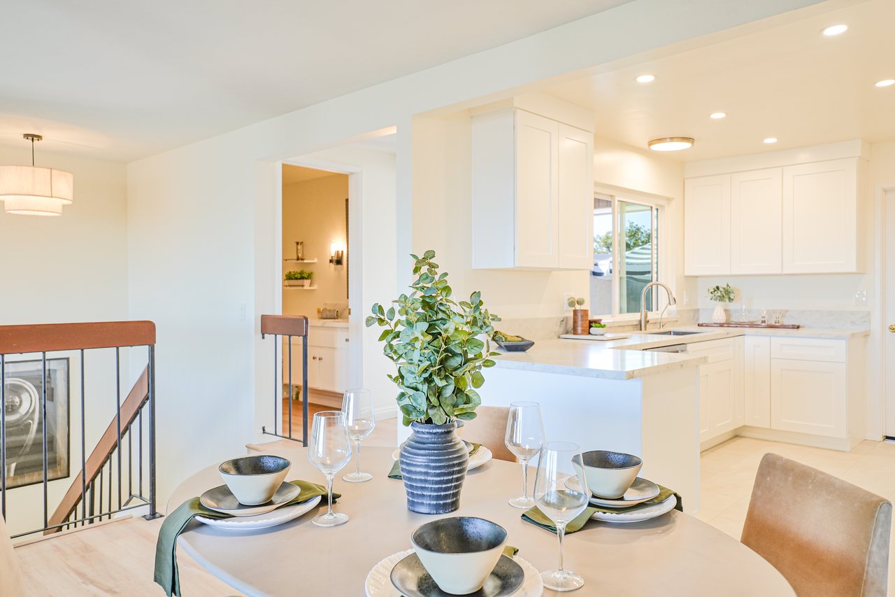 Bright open-concept kitchen and dining room at 6321 Caminito Luisito townhome in San Diego, CA 92111, featuring white cabinetry, updated countertops, natural light, and a modern dining setup.