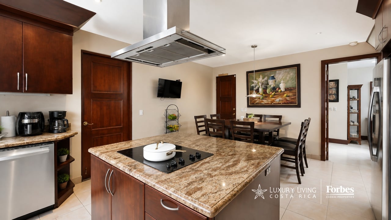 Kitchen with a granite island, dark wood cabinetry, stainless steel appliances, and an adjoining dining area.
