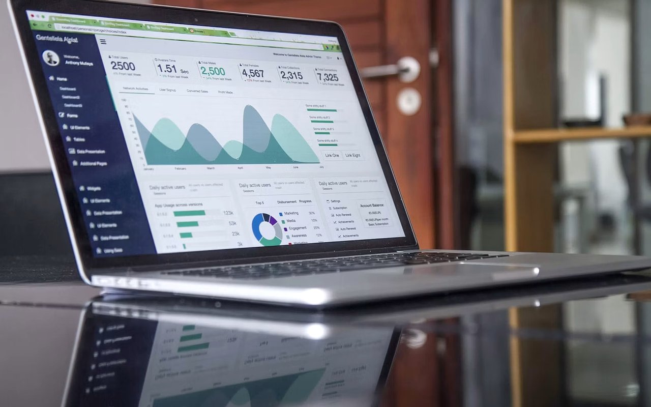 Laptop displaying an analytics dashboard with charts, reflected on a glossy table.