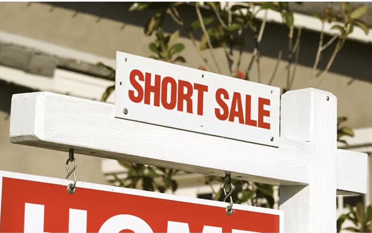 Short sale sign mounted on a white real estate sign frame.