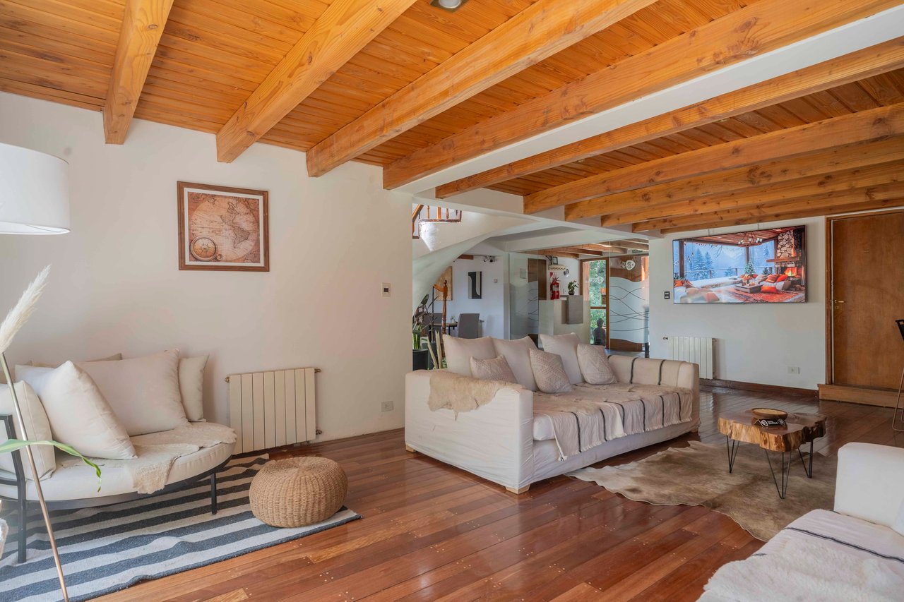 Hotel living room with white sofas beneath an exposed timber ceiling and polished wood floors.