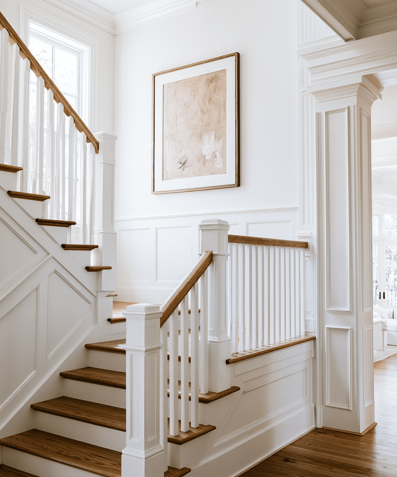 White paneled staircase with dark wood treads and handrails beside tall windows.