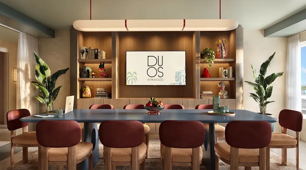 Duos Wynwood dining room with a long table, burgundy chairs, and a wood-paneled display wall.