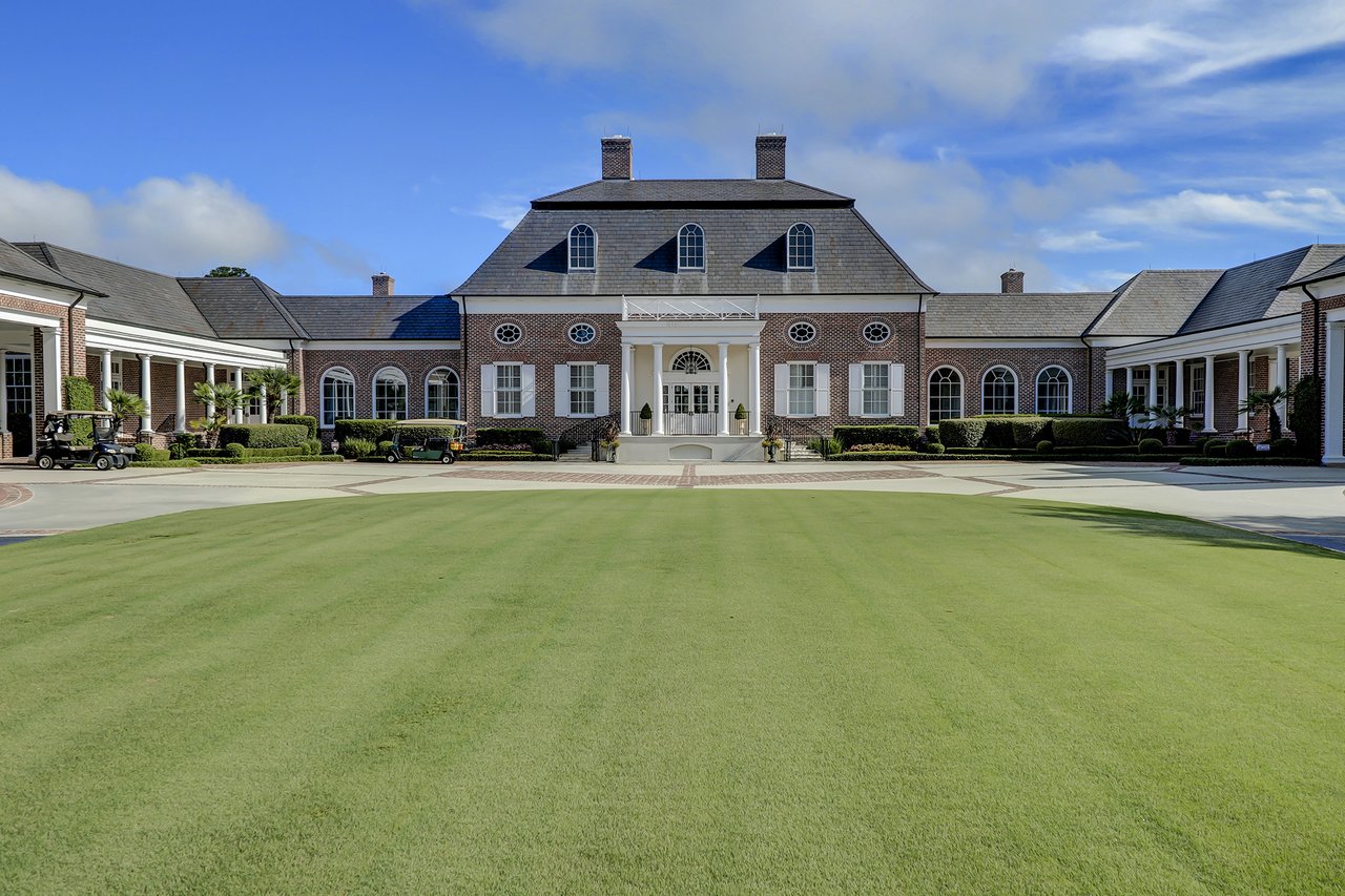 Berkeley Hall clubhouse with a slate roof, white columns, and a broad green lawn.
