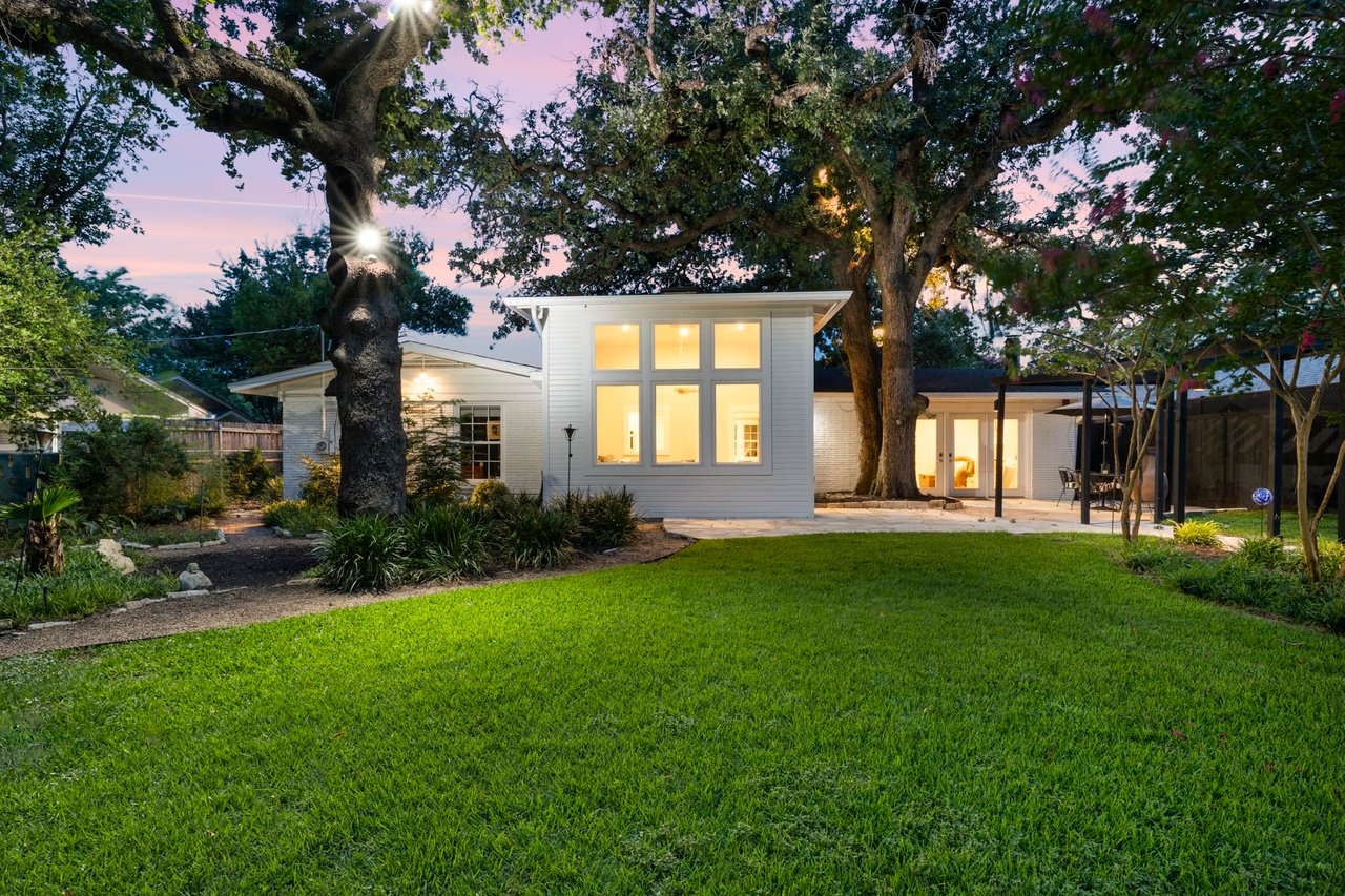 Twilight exterior view of the modern addition beneath mature oak trees, 2404 Westover Rd.