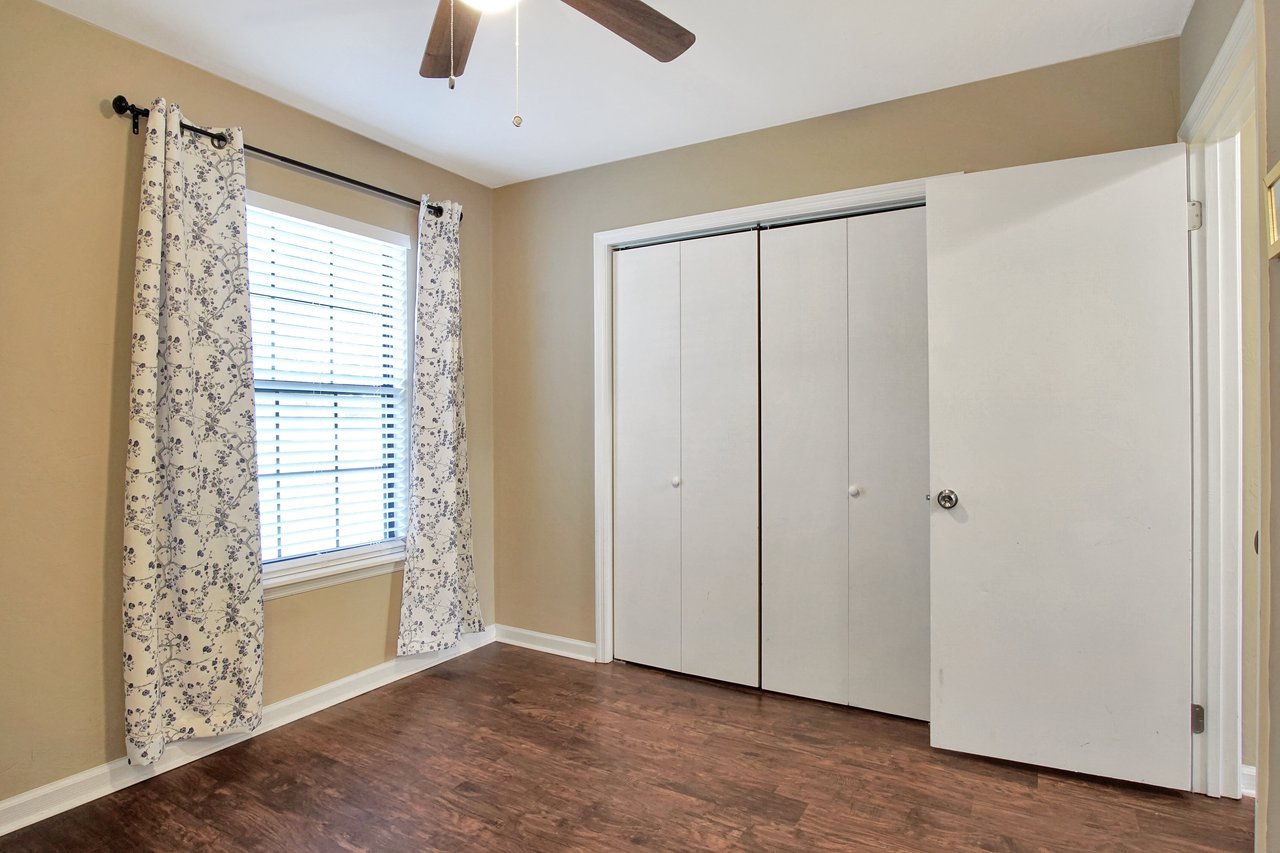 A room featuring a ceiling fan and a door, showcasing a simple and functional interior design.