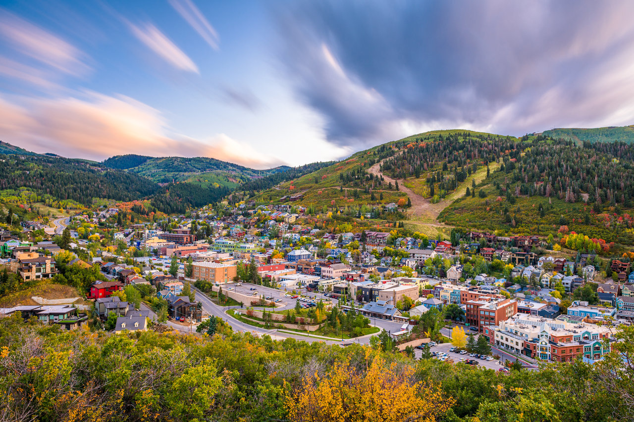 Mountain town nestled in autumn-colored hills beneath a dramatic, cloud-streaked sky.