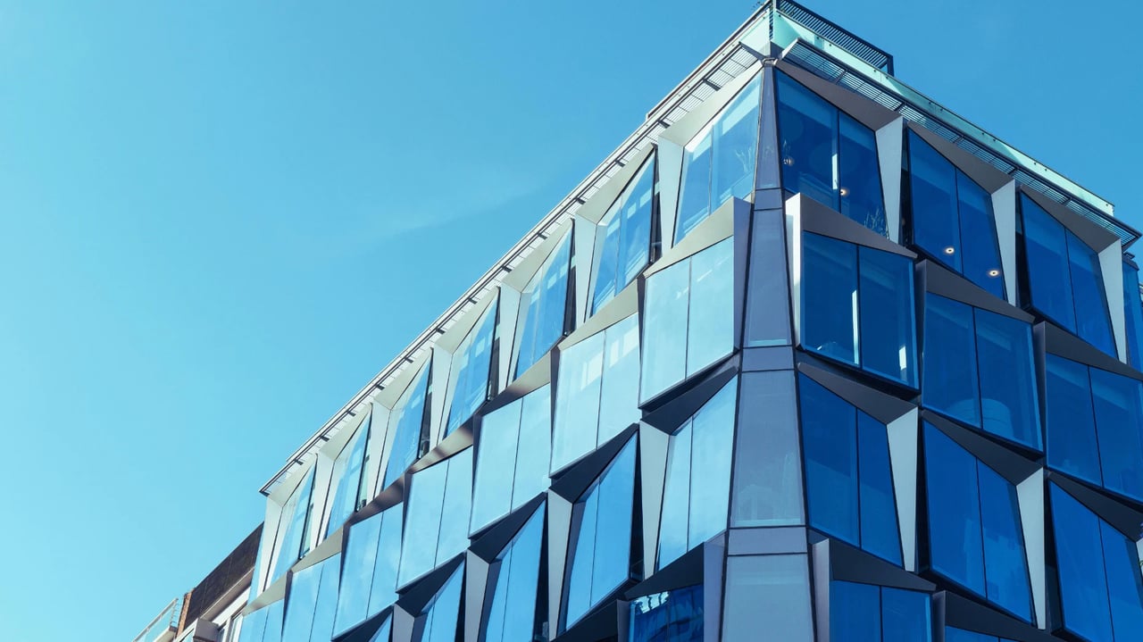 Modern building with an angular facade of blue-tinted glass panels.