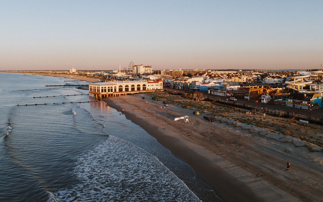 Ocean City shoreline with beachfront buildings, attractions, and waves at golden hour.