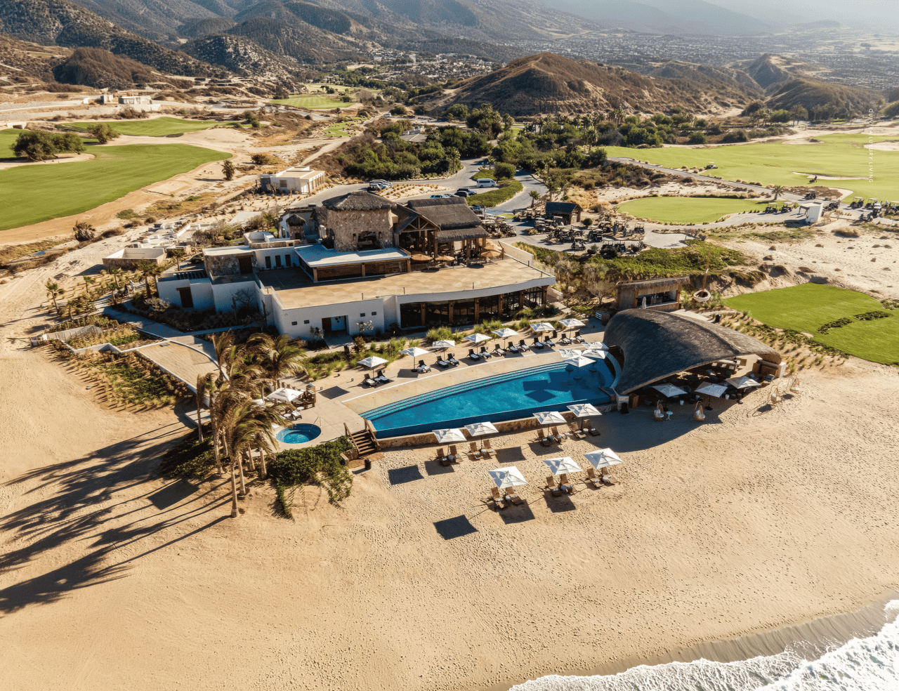 Aerial view of the Quivira private beach club, infinity pool, and golf course on the Pacific