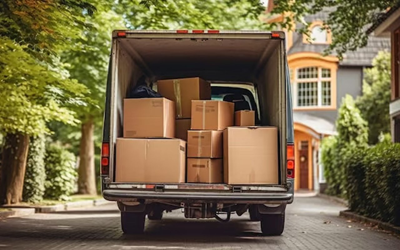 Moving truck loaded with cardboard boxes on a leafy residential street.