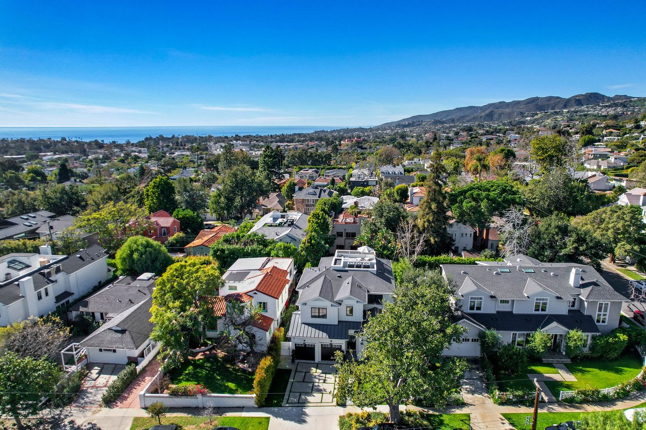  An aerial view of a residential neighborhood with a mix of traditional and modern houses, nestled among abundant green trees and foliage.