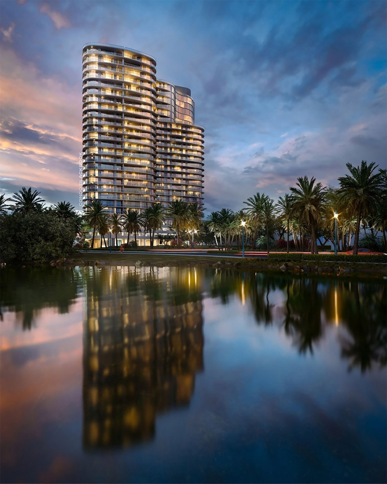 Tal Aventura tower with illuminated rounded balconies reflected in a pond at dusk.