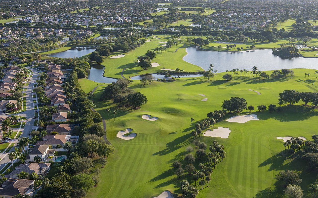 Aerial view of a golf course with lakes, sand bunkers, and homes along the fairways.
