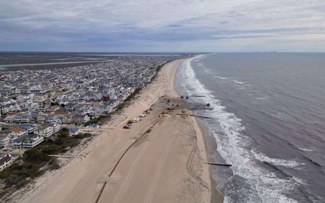 Aerial view of a coastal town, with beach restoration equipment along the oceanfront.