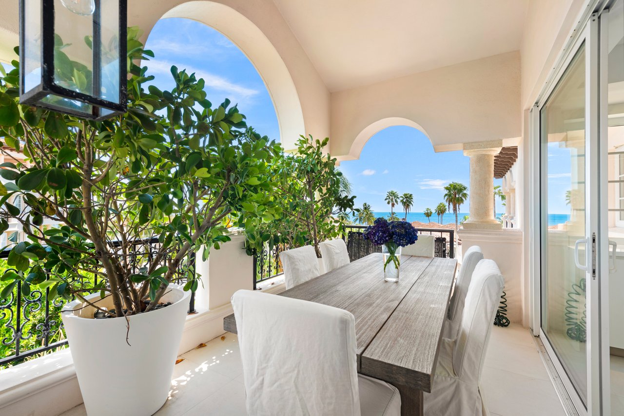 Covered balcony dining area with arched openings and ocean views.