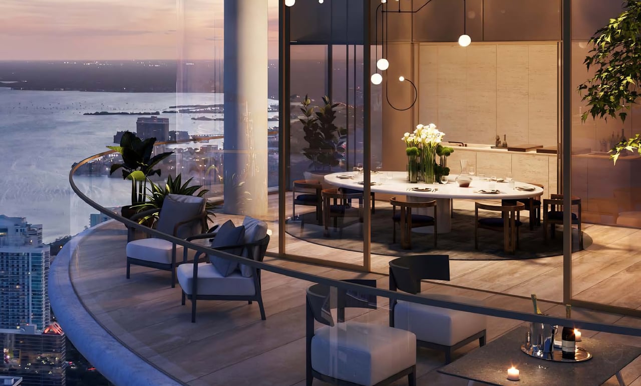 High-rise dining area opening to a curved waterfront terrace with lounge seating at dusk.