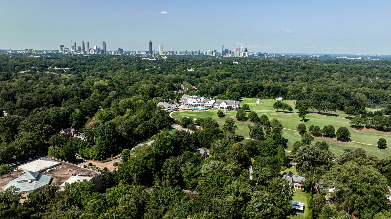 Aerial view of a wooded estate and golf course with the Atlanta skyline in the distance.