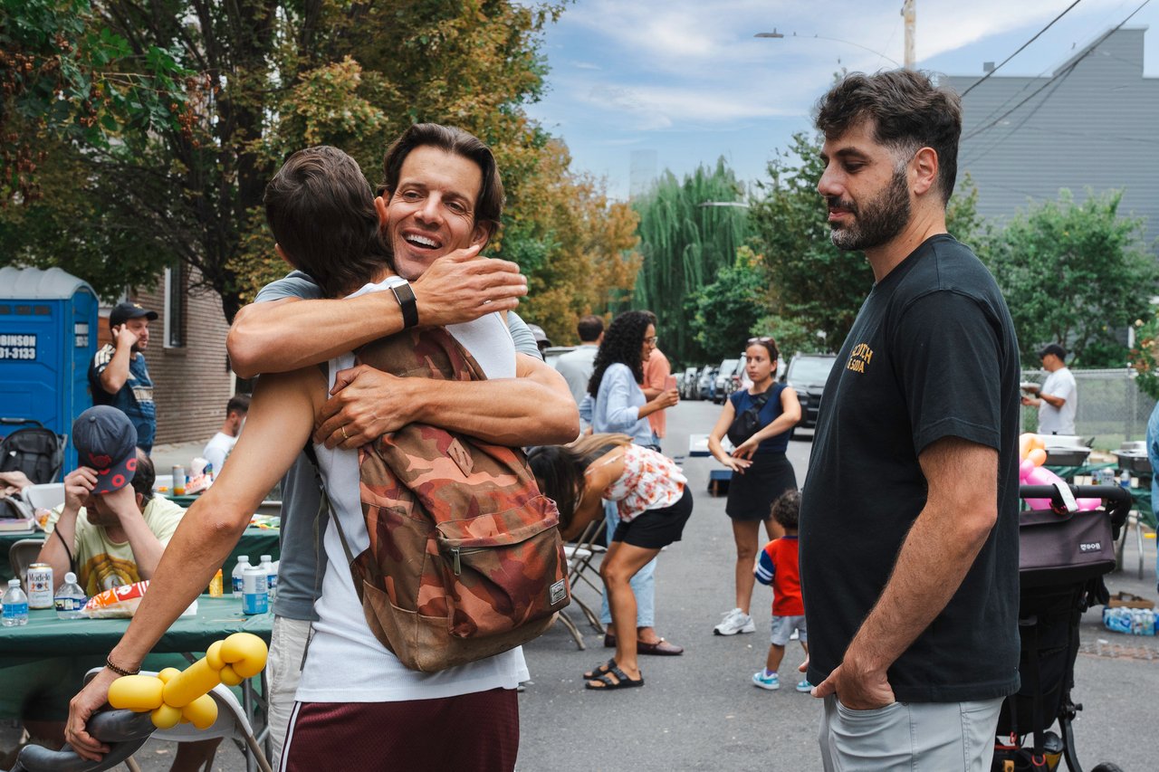 Neighbors embrace and mingle at an outdoor neighborhood block party.