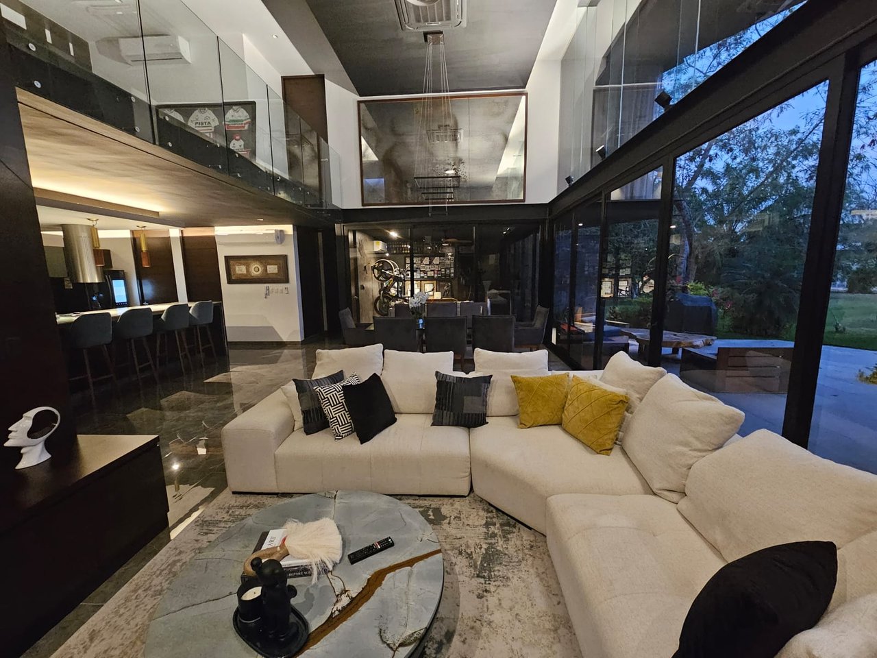 Modern living room with a cream sectional, glass walls, and an open mezzanine overlooking the garden.