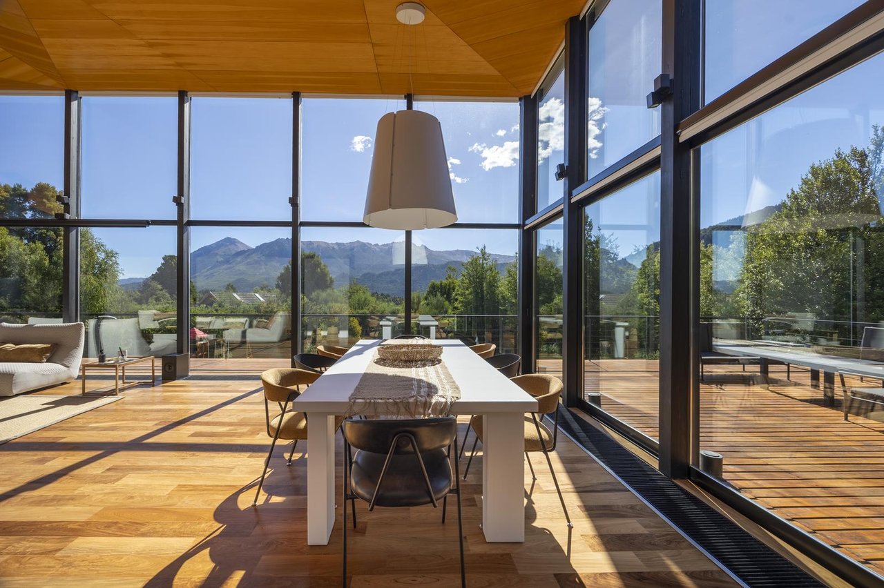 Dining room with a long table, floor-to-ceiling windows, and mountain views.