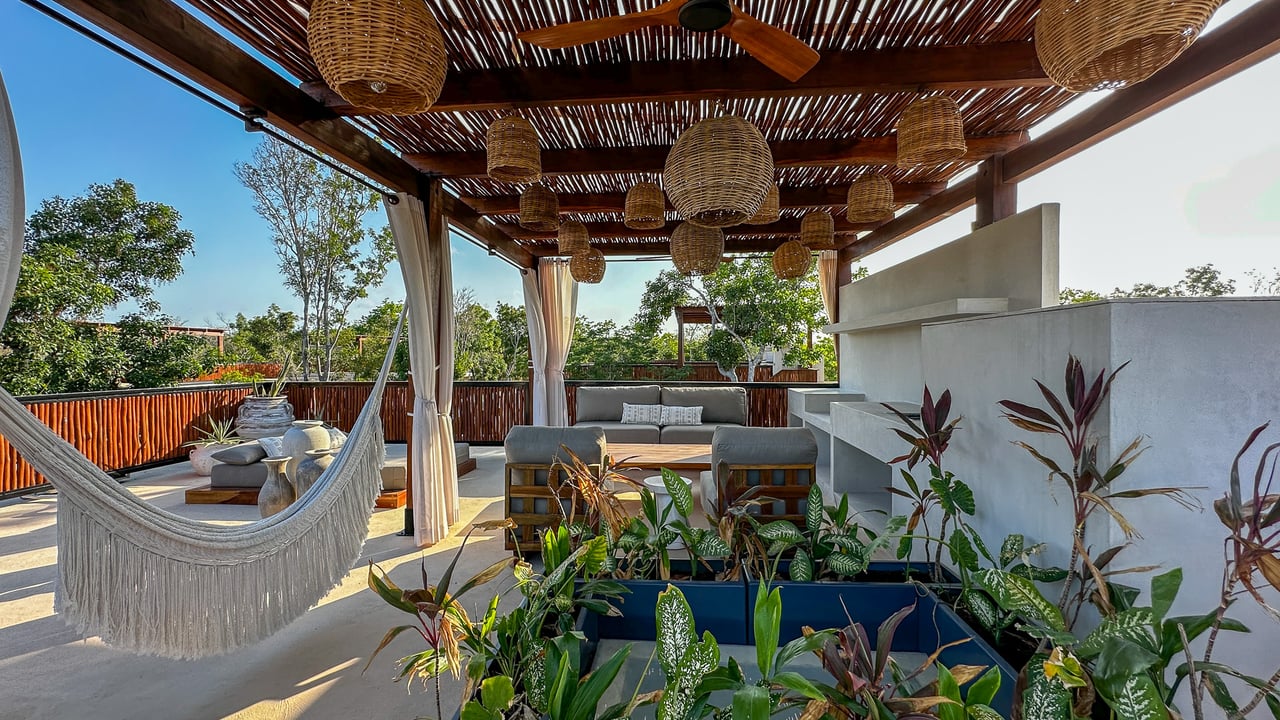 Rooftop terrace with a wood-slat pergola, woven lights, hammock, and outdoor lounge seating.