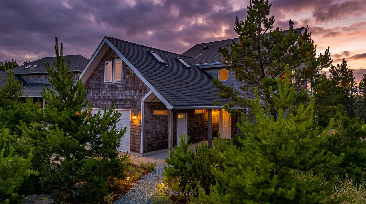 Sold Pine Ridge home at 34470 Pinyon Dr in Manzanita, Oregon, listed by Meadow Davis of Home + Sea Realty, with vaulted ceilings, greenbelt views, a wood stove, sunroom, and two-car garage.